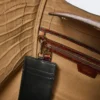Pequena bolsa marinha em pele com padrão de crocodilo, castanha